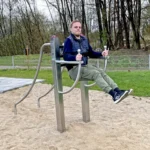 Foto des Beinheber-Liegestütz-Kombitrainers, er steht auf einer feinen Sandfläche und ein Mann führt darauf die Übung Beinheben aus.