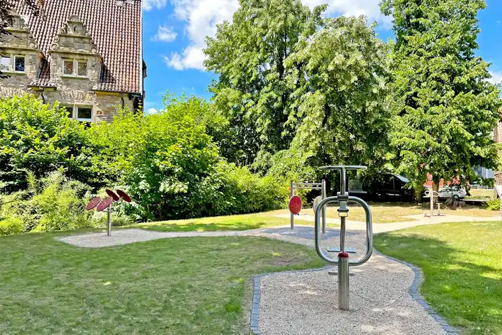 Luftaufnahme von Fachwerkhäusern mit roten Dächern in einem Dorf, Bäume und Park im Vordergrund.