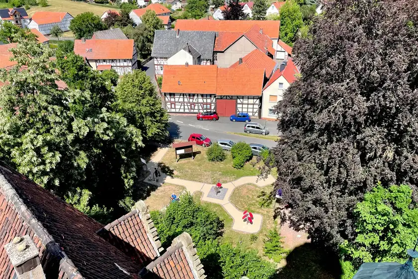 Luftaufnahme von Fachwerkhäusern mit roten Dächern in einem Dorf, Bäume und Park im Vordergrund.